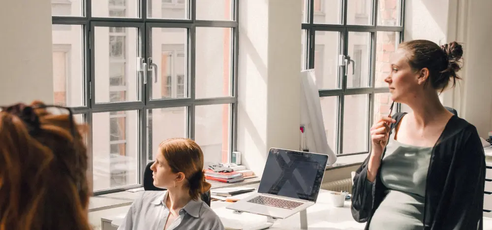 Several employees brainstorm in a brightly lit office.