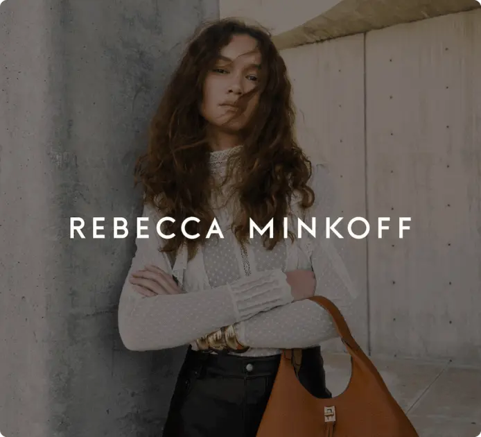 Eine Frau mit langen Haaren in weißer Bluse trägt eine braune Handtasche. Darüber steht: „Rebecca Minkoff“.