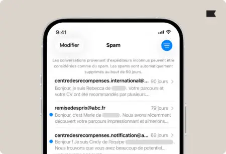iOS-26-spam-folder Écran d'un iPhone affichant des e-mails marqués comme spam, avec des expéditeurs inconnus et des aperçus de messages.
