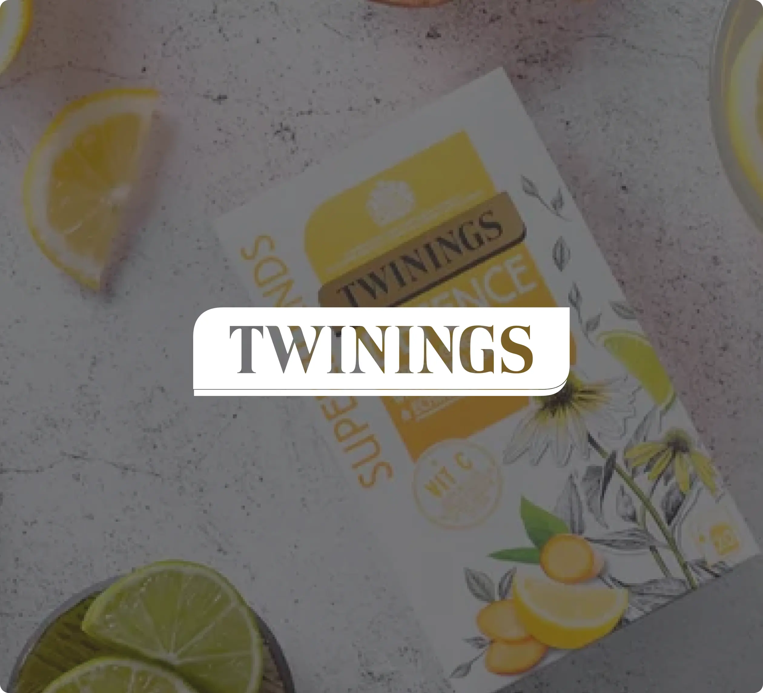 Boîte à thé Twinings avec tranches de citron jaune et quartiers de citron vert sur une surface texturée