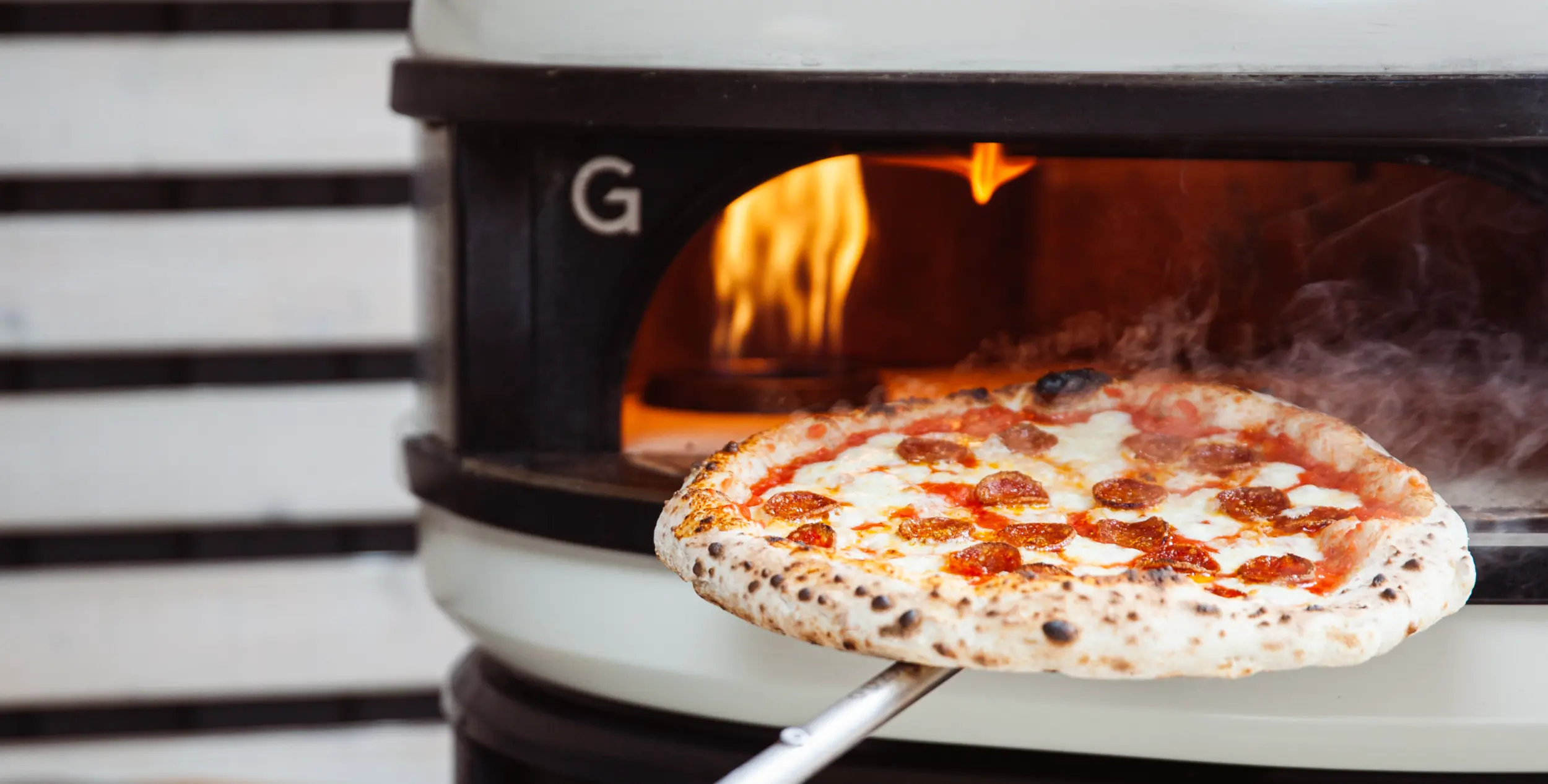Una pizza con salame viene infornata in un forno Gozney