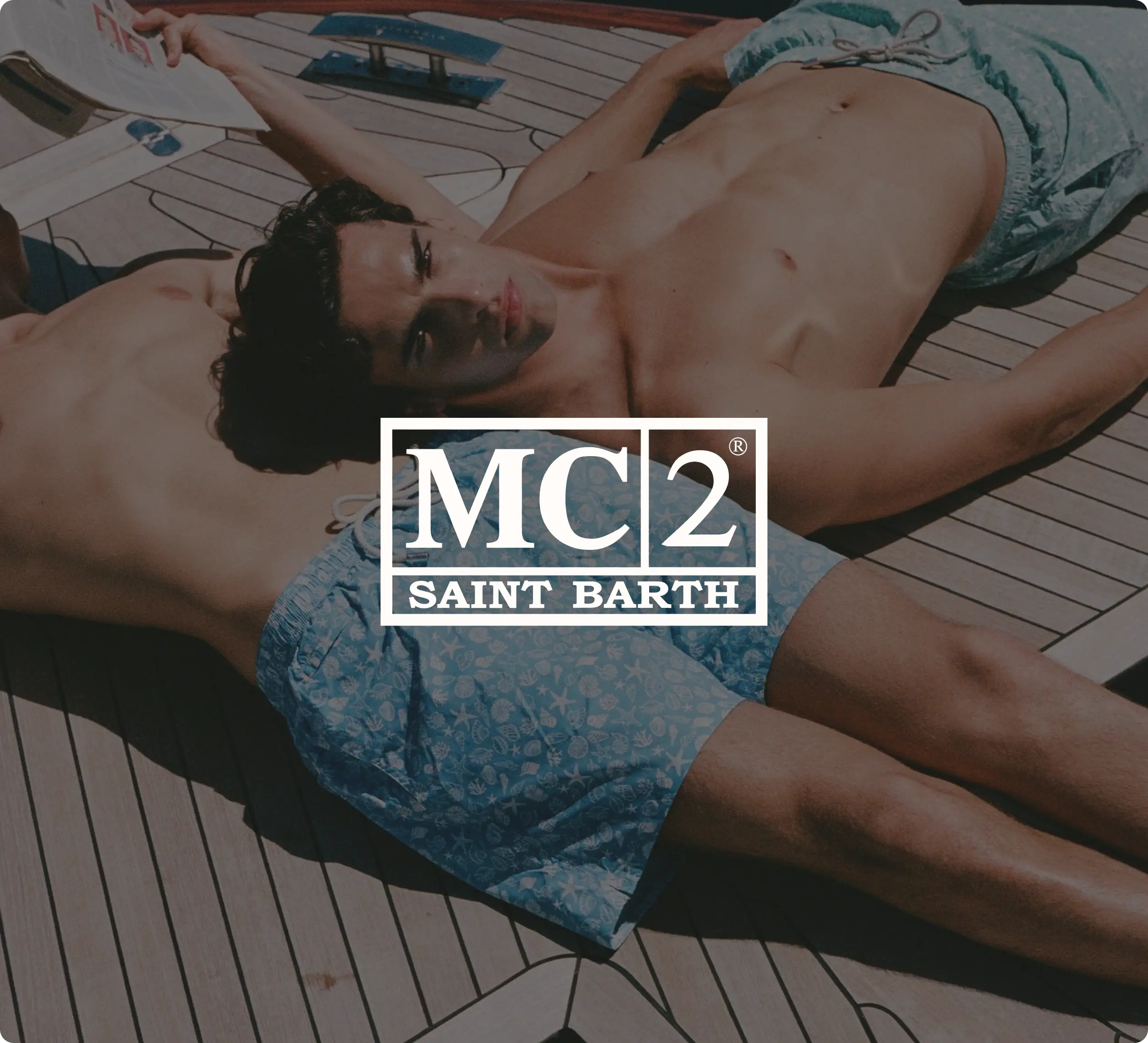 Due uomini in costume da bagno MC2 Saint Barth sdraiati su una barca.