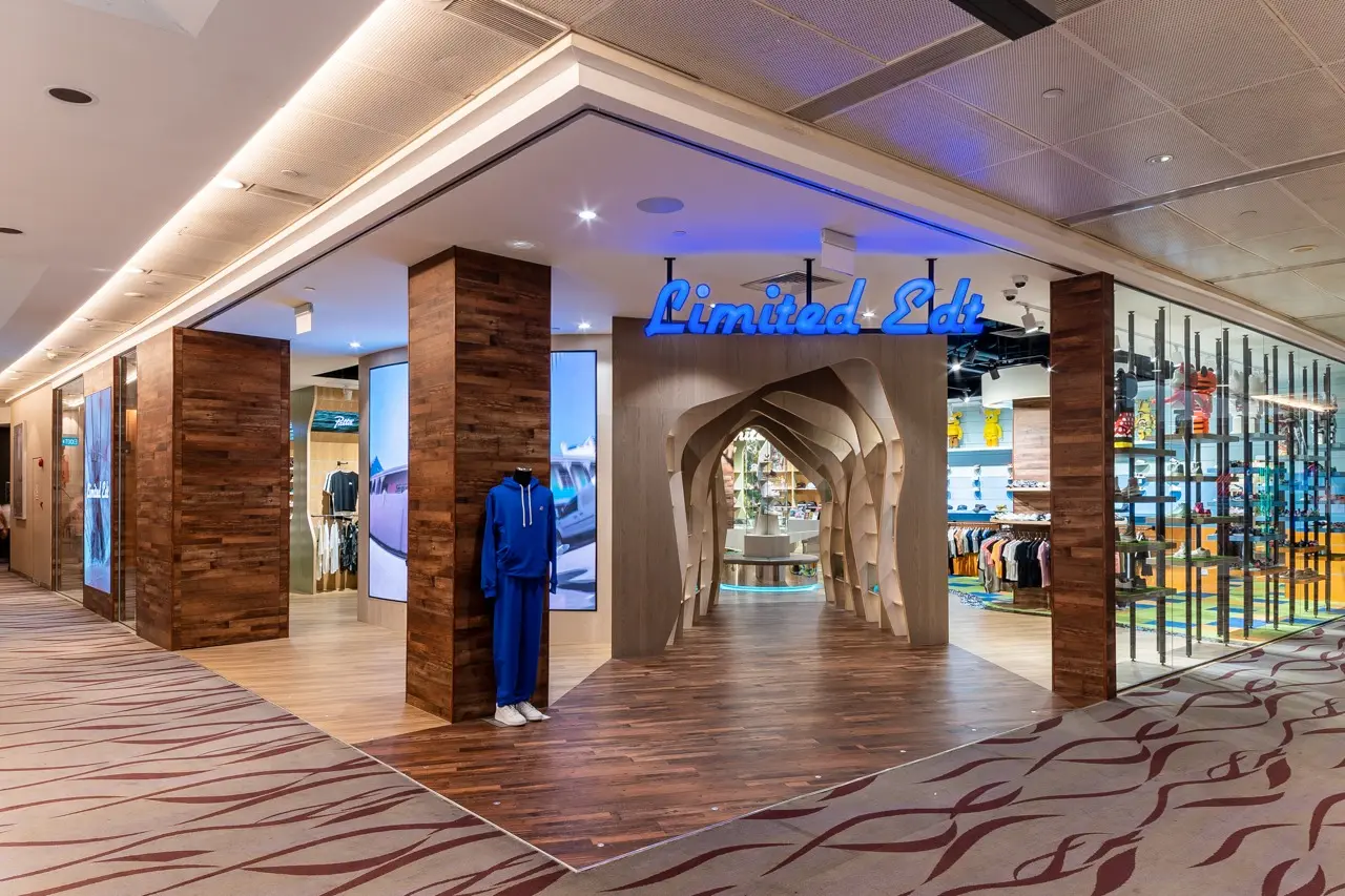 Limited Edt store entrance with wooden accents, blue neon sign, and a mannequin in a blue tracksuit. Clothing and accessories inside.