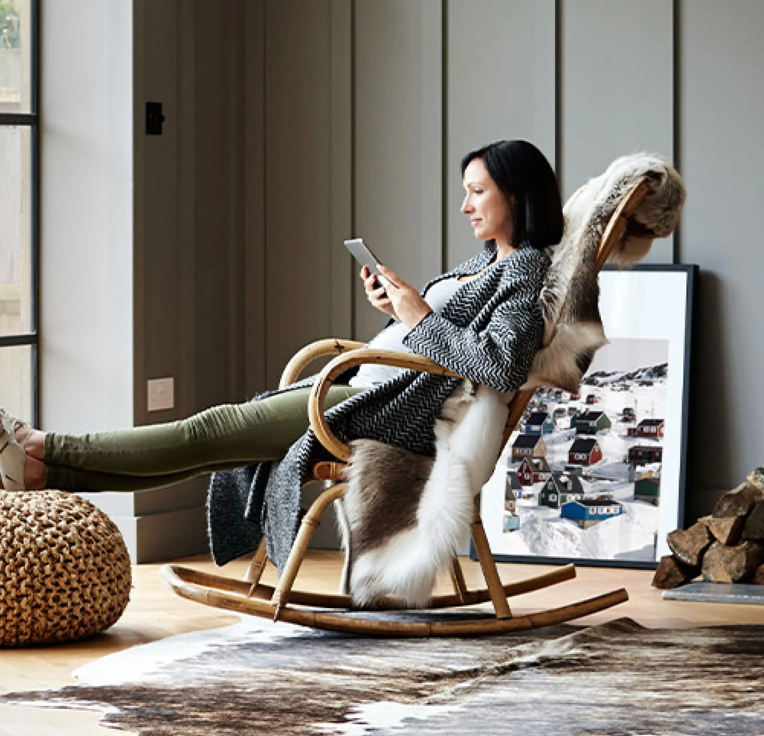 A woman in a rocking chair reading her tablet at home