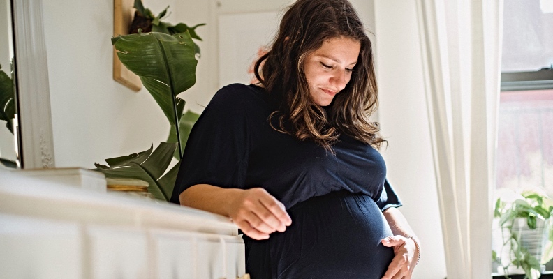 Pregnant woman cradles her bump