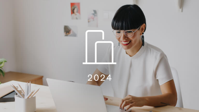 A woman looks at her laptop. Overtop of the photograph is an icon of a bar graph representing Klaviyo benchmarks. The year 2024 is below the icon.