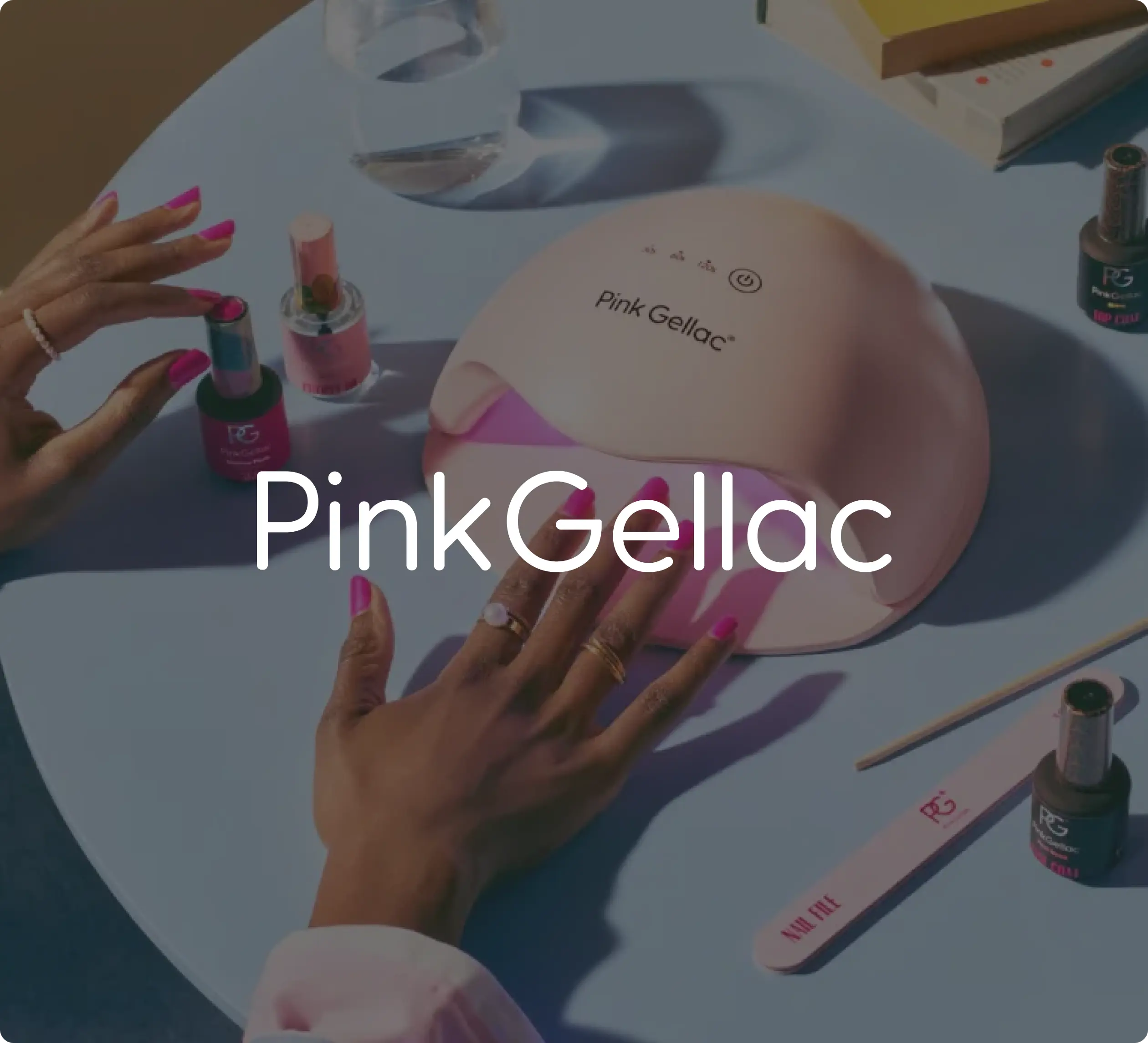 Hands applying Pink Gellac nail polish with a UV lamp on a table.
