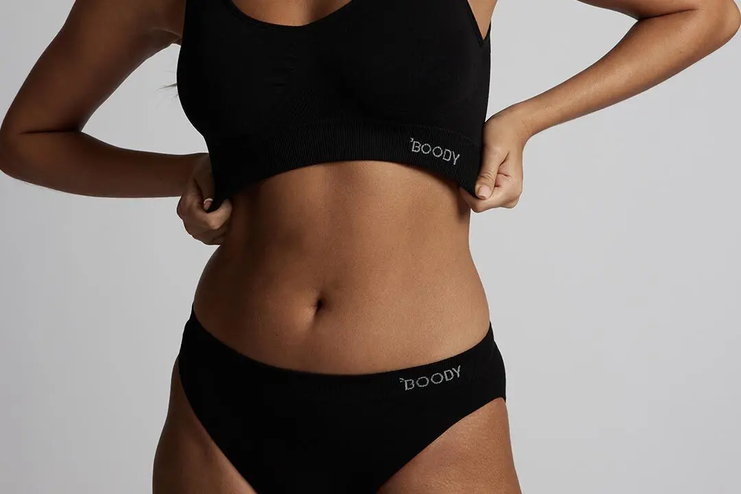 Person wearing black Boody underwear set, adjusting the top.