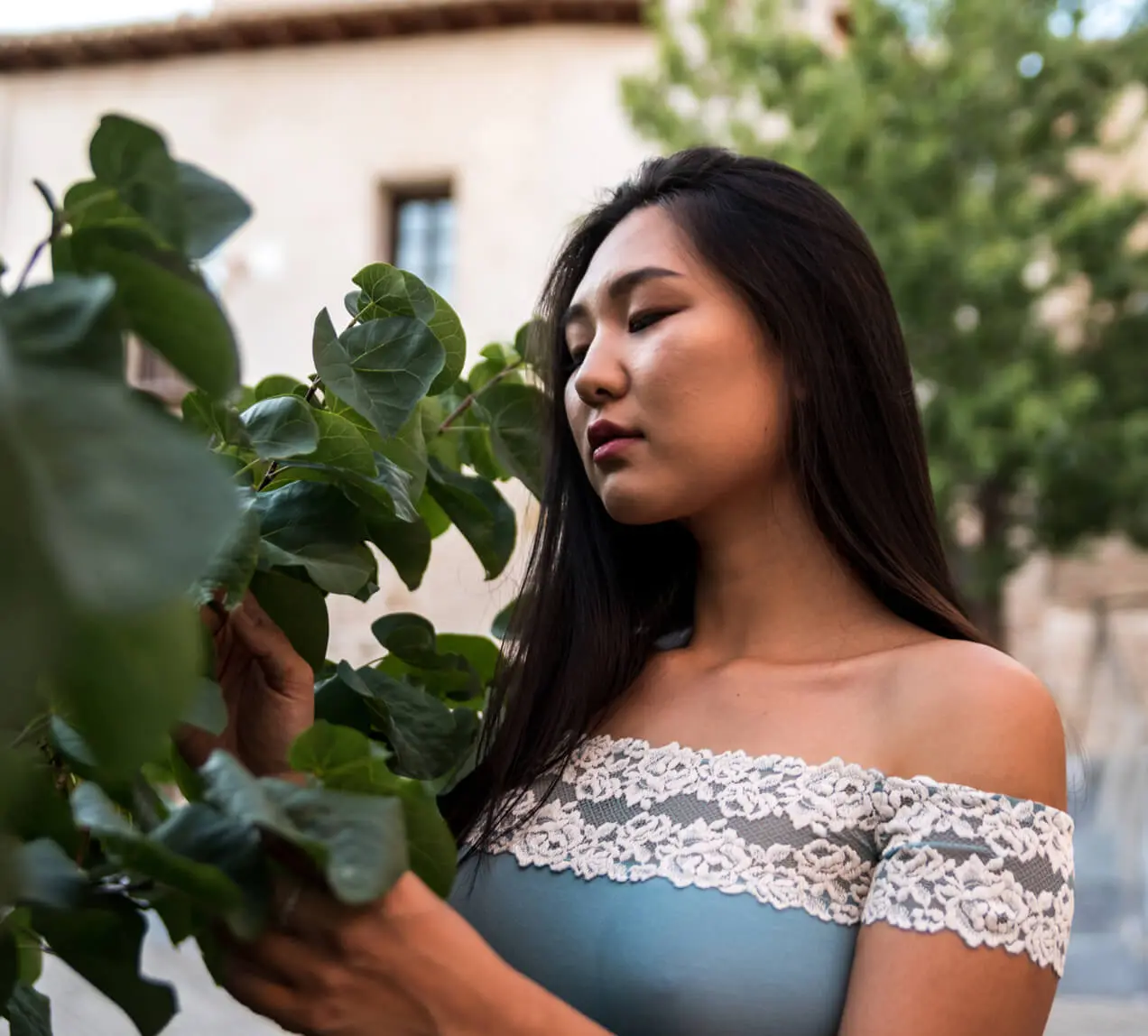 A woman wears a blue lacy top outdoors.