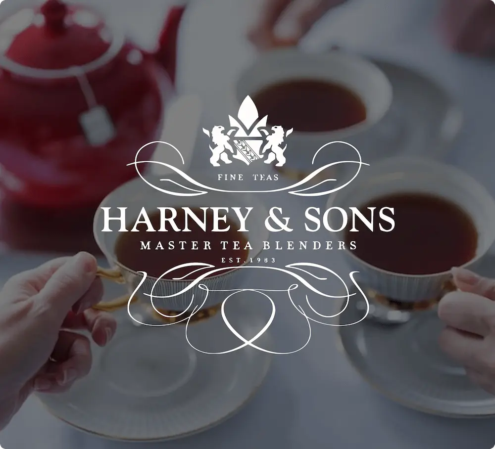 Harney & Sons logo overlaying an image of two hands holding teacups, with a red teapot in the background.