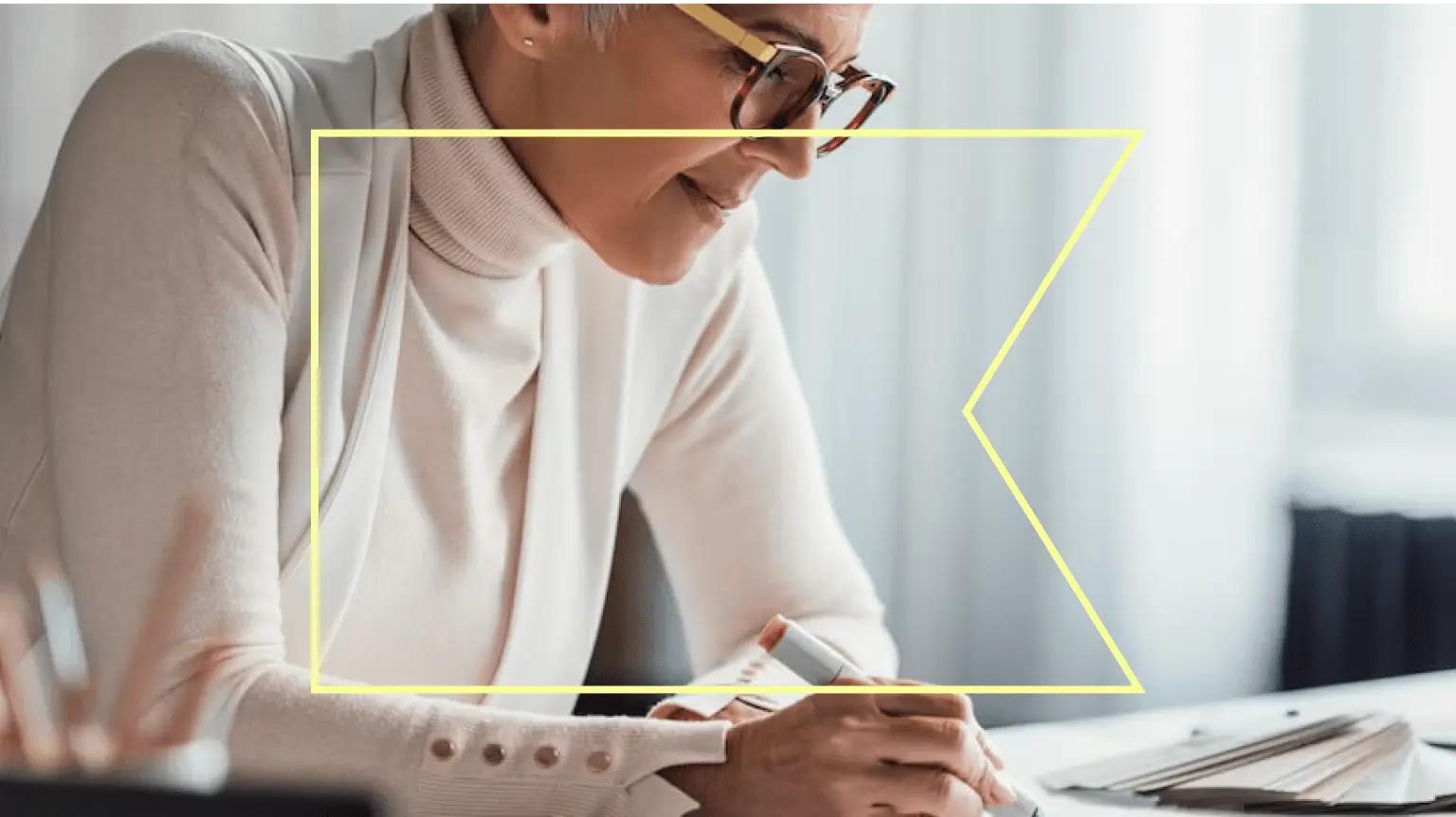 A yellow outline of the Klaviyo flag over a person wearing glasses, looking down while writing with a marker