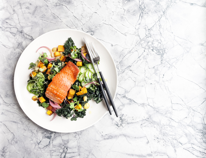 Image shows a piece of salmon on a plate with greens.